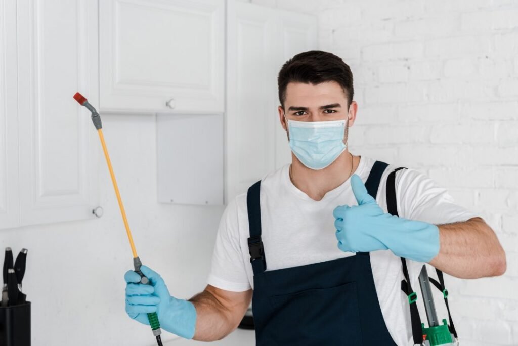 exterminator-in-uniform-holding-toxic-spray-and-showing-thumb-up.jpg
